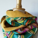 Tour de cou vert avec des motif coloré doublure jaune posé sur un mannequin de couture